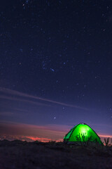 Acampando en la cima de la montaña observando la ciudad de Puebla con un cielo estrellado con la constelación de orión 