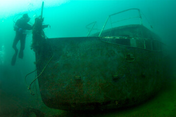 Scuba diver explores a ship wreck in a fresh water lake.