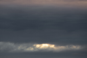 Obraz premium Dramatic evening sky with dark clouds and sun light in the background.