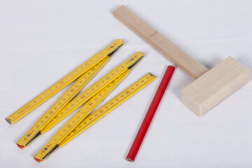 Pencil, wooden hammer and ruler for kids on white backdrop. Close up photo.