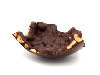 A piece of dark chocolate easter egg with hazelnuts isolated on white background
