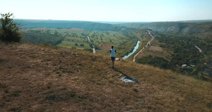 Aerial drone footage with man running on hills during summer