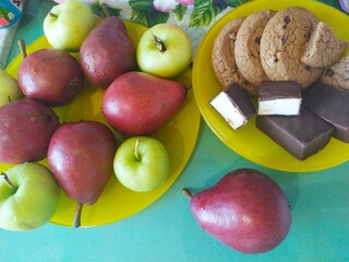 Dark red pears green apples and cookies on a yellow plate