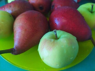 Dark red pears green apples and cookies on a yellow plate