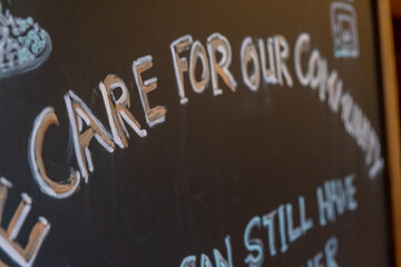 A handwritten sign at a pub saying care for our community as pubs and restaurants begin to open again as the covid lockdown eases in the UK