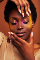 Fototapeta na wymiar young pretty african girl with bright colorful makeup and manicure posing cheeful on brown background, lifestyle people concept