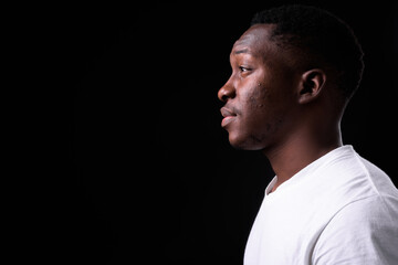 Young handsome African man against black background