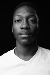 Young handsome African man against black background in black and white