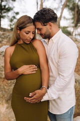 Fototapeta premium Portrait cheerful pregnant couple looking to each other in the park