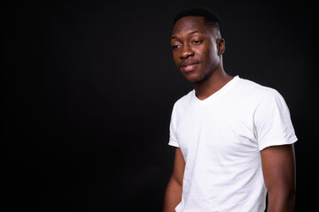 Young handsome African man against black background