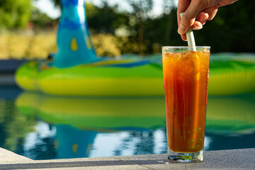 hand stirring homemade bubble tea with straw at pool
