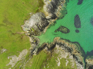 West coast of Ireland. Aerial drone top down view. Green fields and rocky shore. Rocks under water...