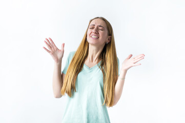 A girl is standing on a white background with her hands up and waiting for good news.