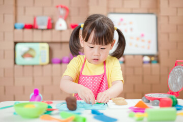 young  girl pretend play food preparing role against cardboard blocks kitchen background