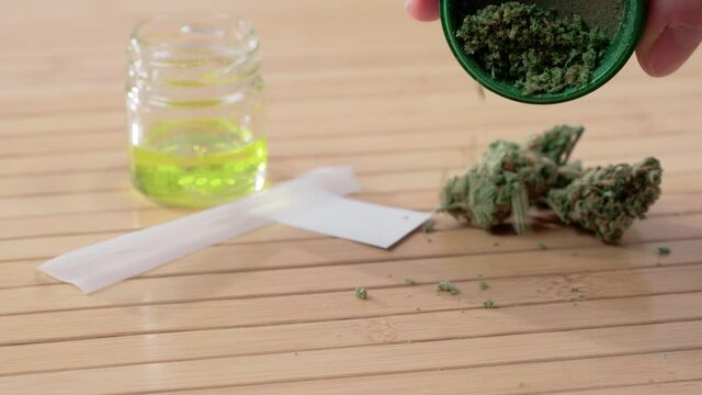 Close up of empty the crusher with papes cannabis oil and a heap of medical marijuana shot in 4k super slow motion