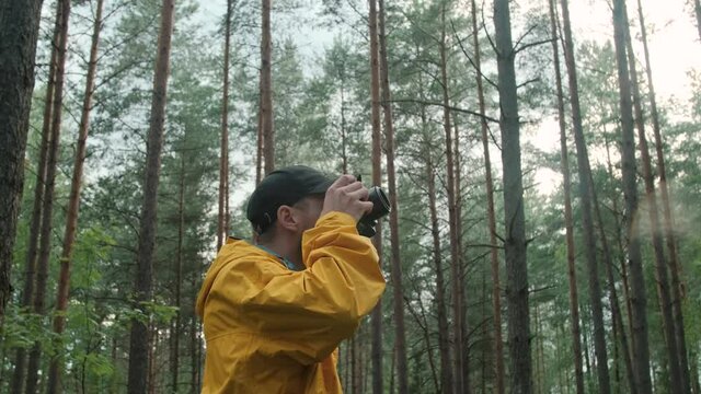Male photographer is taking photographs in a forest at autumn time.