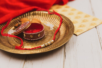 Fototapeta na wymiar Raksha Bandhan - Traditional plate (Thali) with Rakhi (Hand Band), and defocused props.