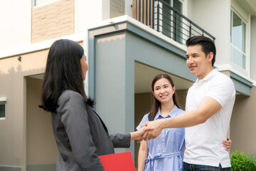 Obraz premium Happy Asian couple looking for their new house and shake hands with real estate broker after a deal. Young couple handshaking real estate agent after signing contract for buy house..