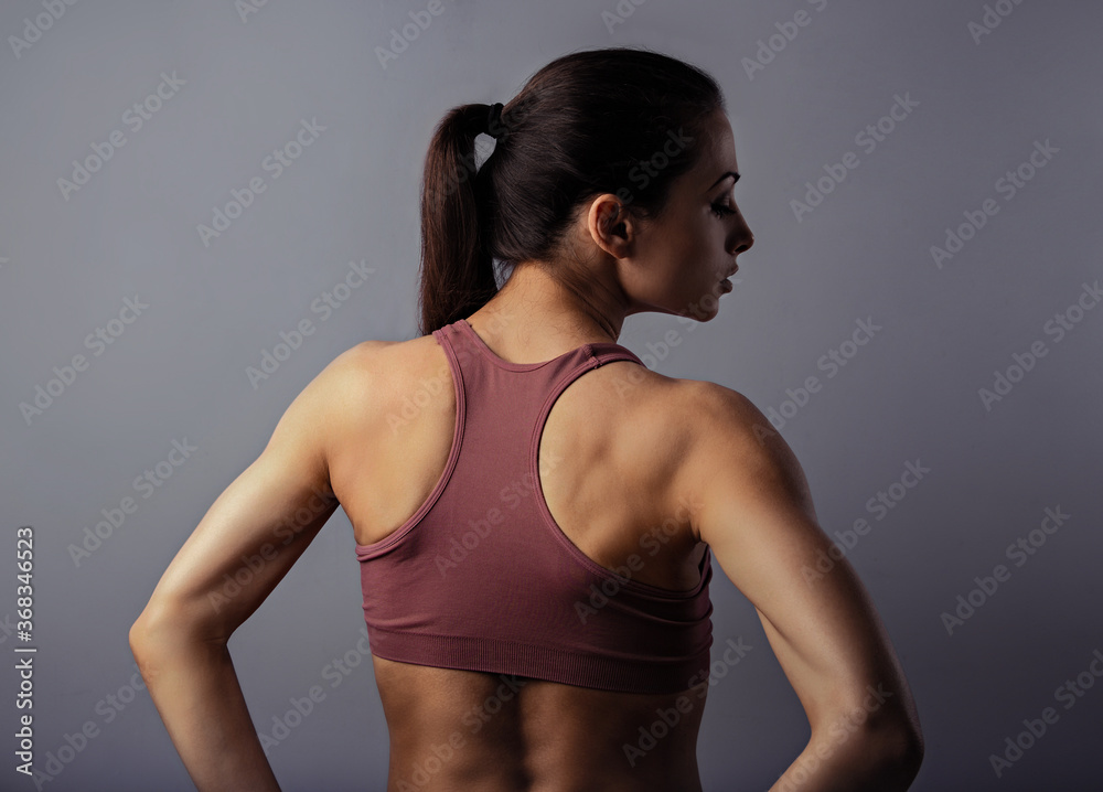 Wall mural sporty strong healthy body young woman posing in sport top on violet background with empty copy spac