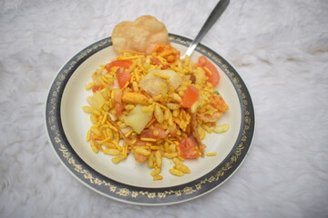 Bhel puri savoury snack Chaat item from India. Popular road side foos dish served in plate spoon. Made of puffed rice, tamaring sauce
