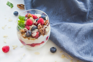Healthy blueberry, raspberry and walnut parfait in a glass on a white background