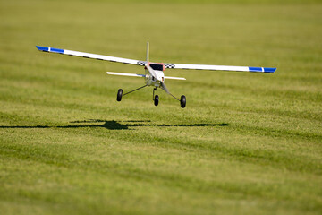 Ein ferngesteuertes Modellflugzeug landet auf einer Wiese auf einem Modellflugplatz.