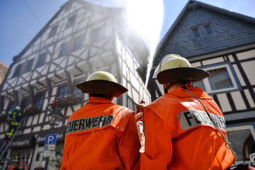 Zwei Feuerwehrleute bei einer Löschübung in einer historischen Altstadt.