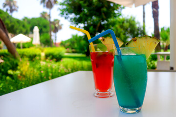 Fresh ice juicy exotic cocktails on the table against the background of blurred greenery. Summer vacation and recreation concept. Copy space for text