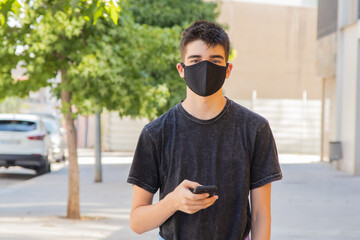 young man with mask and mobile phone on the street