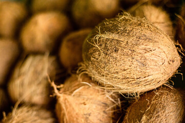 Close up of dehusked coconut pods in a street shop. Front view. Fresh tropical fruits and vegetables copy space blurred background 