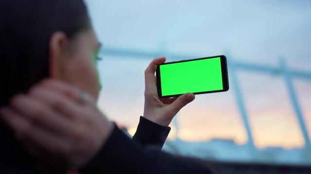 Woman taking selfie photo on smartphone with green screen. Mobile phone