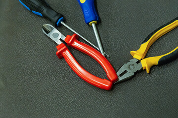 Nippers rubber handles with red and blue screwdriver on dark background desktop repair tool kit