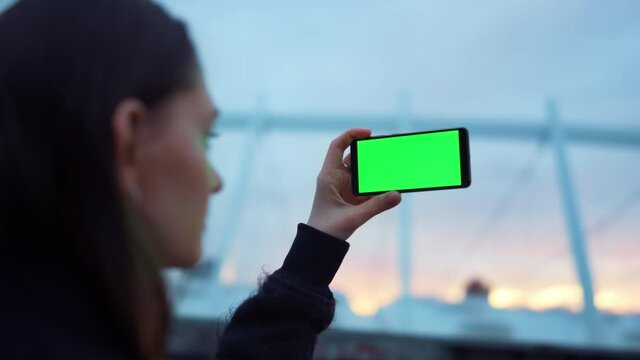 Girl taking picture on cellphone with green screen. Lady using mobile phone