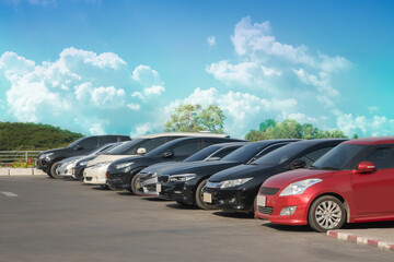 Car parked in large asphalt parking lot with white cloud and blue sky background. Outdoor parking...