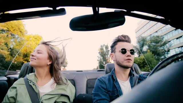joyful young couple ride a convertible around the city in the summer and sing songs. Car travel concept.