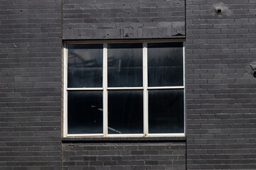 White window frame around black brick wall.