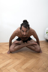 Fototapeta na wymiar A young Afro European male Yogi does meditation and Hatha Yoga workout at home during lockdown.