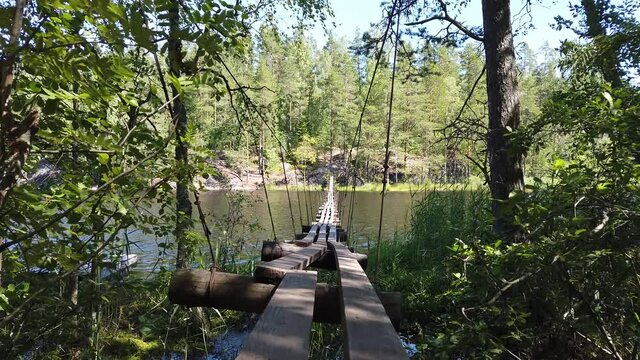Suspended wooden bridge across the lake. summer day. green forest. nature landscape