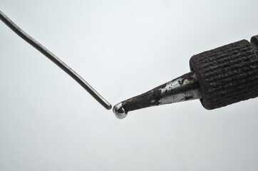 Soldering iron touching wire on a white background. Macro photograph