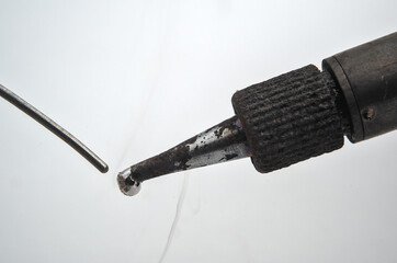 Soldering iron touching wire on a white background. Macro photograph