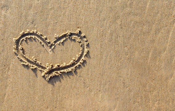 heart on the sand.
A heart written with a finger on the wet sea sand on the left and with a place for text on the right, close-up top view.