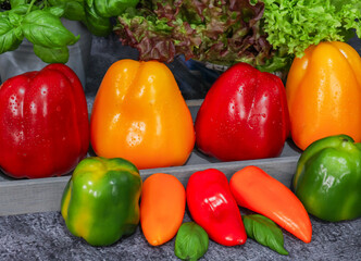 red and yellow peppers
Red, yellow and green peppers in a wooden tray on a stone background, close-up side view.