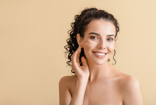 Beautiful young woman with foundation on her face against color background