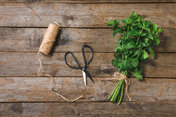 Fresh green mint, thread and scissors on wooden background
