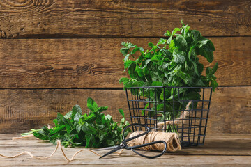 Fresh green mint, thread and scissors on wooden background