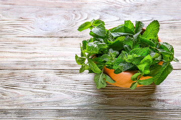 Fresh green mint in bowl on wooden background