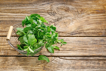 Fresh green mint in basket on wooden background