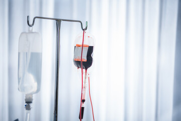 Close-up of Red blood bag and normal saline hanging in hospital ward - Powered by Adobe