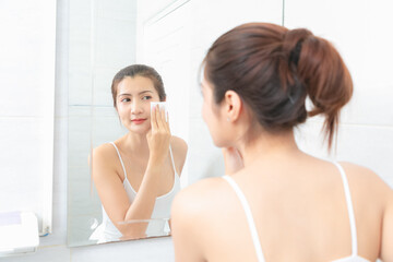 Obraz na płótnie Canvas Beautiful Asian Woman applying cosmetic cream in bathroom.