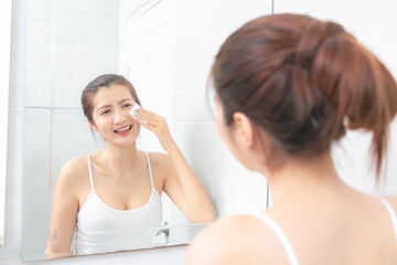 Obraz na płótnie Canvas Beautiful Asian Woman applying cosmetic cream in bathroom.